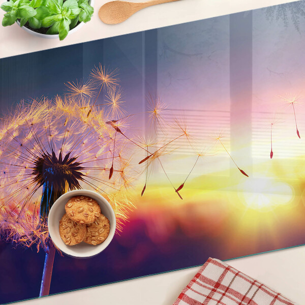 Glazen snijplanken Paardenbloemen tegen de achtergrond van de zonsondergang