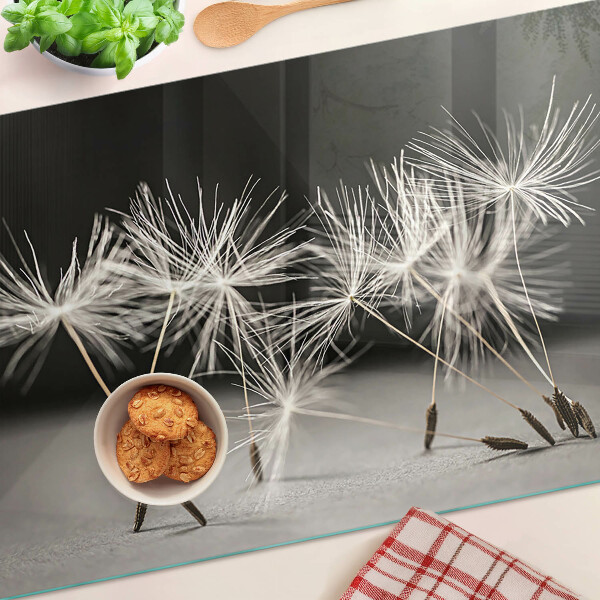 Snijplanken van glas Pluizige paardenbloemen op een monochrome achtergrond.