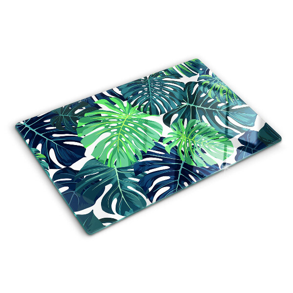 Glazen snijplanken Monstera-bladeren op een tropische achtergrond
