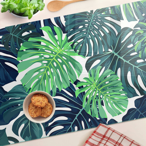 Glazen snijplanken Monstera-bladeren op een tropische achtergrond