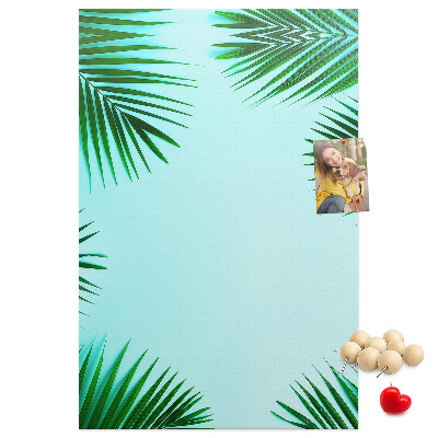 Memobord van kurk met palmbladeren op een blauwe achtergrond