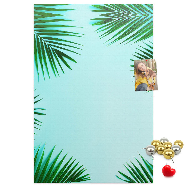 Memobord van kurk met palmbladeren op een blauwe achtergrond