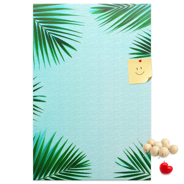 Memobord van kurk met palmbladeren op een blauwe achtergrond