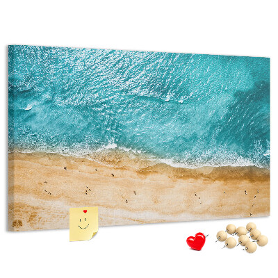 Kurkbord met een afbeelding van een strand met golven en voetsporen