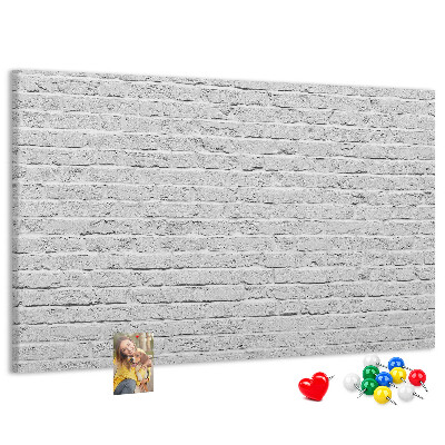 Kurk prikbord met afbeelding van witte bakstenen muur met kleurrijke punaises