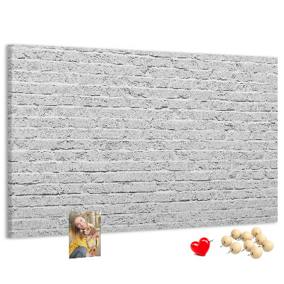 Kurk prikbord met afbeelding van witte bakstenen muur met kleurrijke punaises