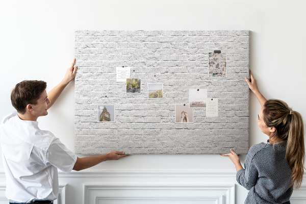 Kurk prikbord met afbeelding van witte bakstenen muur met kleurrijke punaises