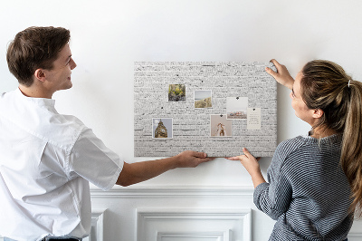 Kurk prikbord met afbeelding van witte bakstenen muur met kleurrijke punaises