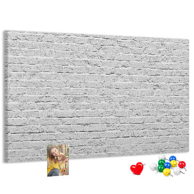 Kurk prikbord met afbeelding van witte bakstenen muur met kleurrijke punaises
